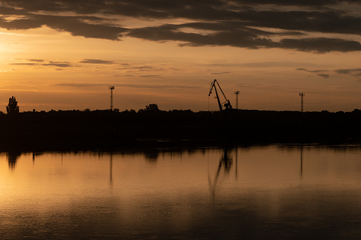 Silhouette and reflection of a crane and towers at sunrise