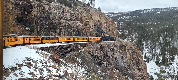 Beautiful scene of an old fashioned train riding through the mountains in winter with snow.