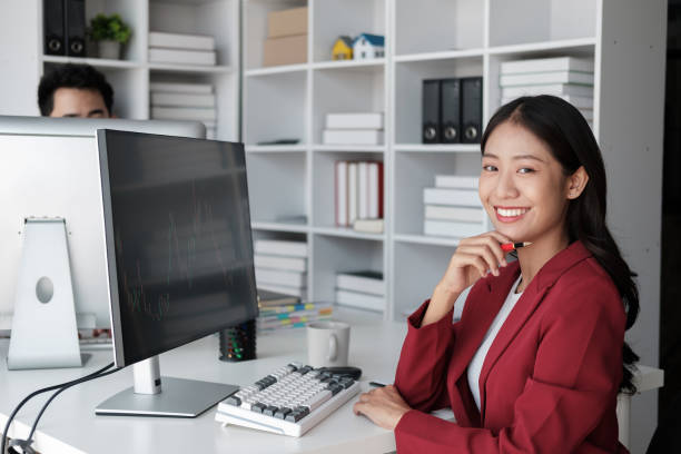 istock Beautiful Asian businesswoman in red blazer working in the office room, using desktop computer. 1572292113