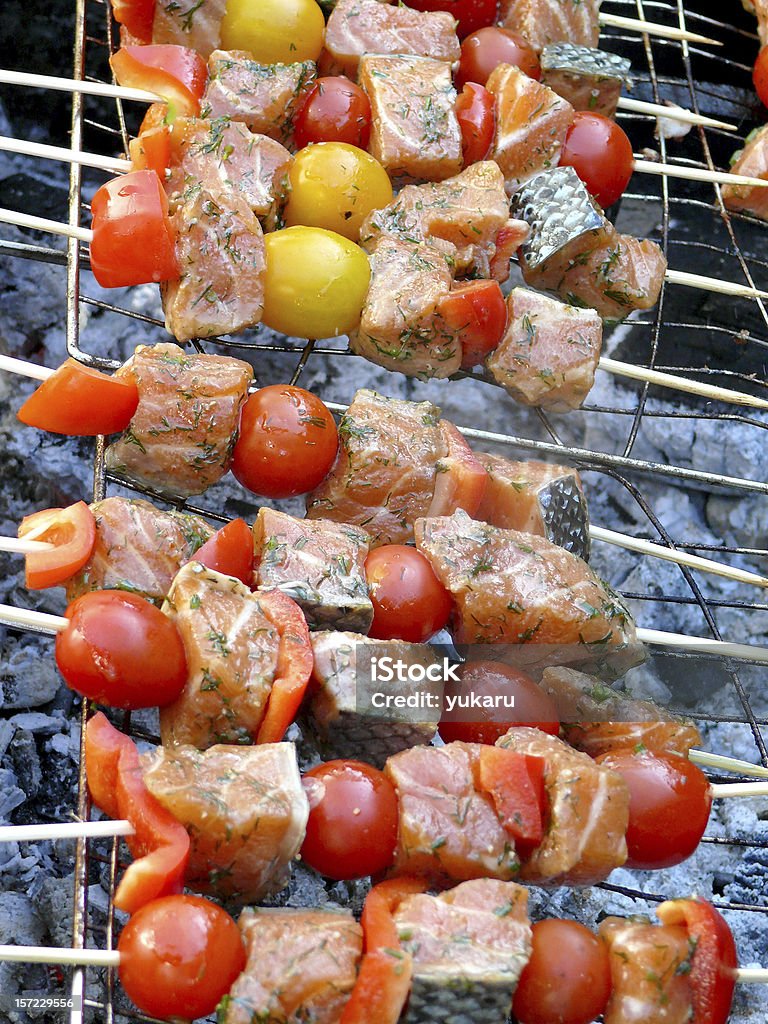 Barbecued salmon on grill with cherry tomatoes salmon pieces on skewers on grill with vegetables Barbecue - Meal Stock Photo