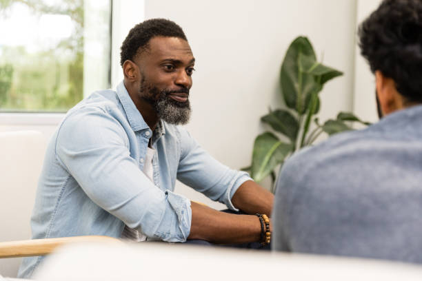 Two men meet in office to talk A mid adult man and an unrecognizable young adult man meet in an office to talk together. office buddies stock pictures, royalty-free photos & images