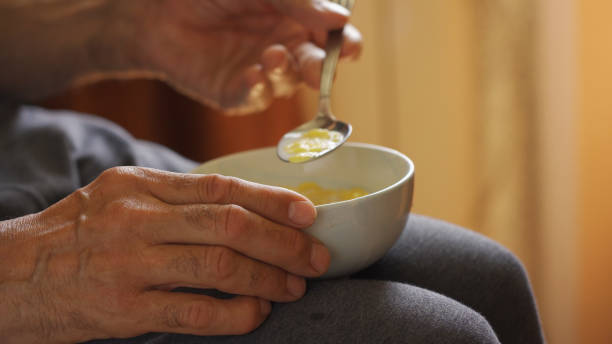 istock The older man's hands hold the bowl in his lap during breakfast. 1572313402