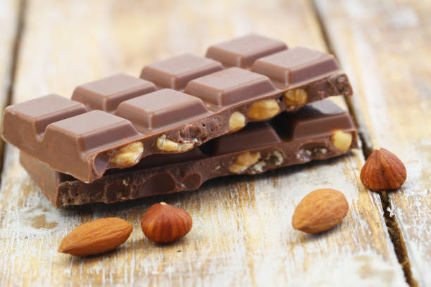 istock Two milk chocolate pieces with whole hazelnuts and almonds on rustic wooden surface 1572316124