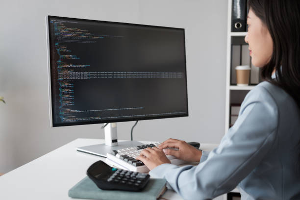 istock Young beautiful Asian businesswoman or programmer working  in her office room with desktop computer. 1572330126