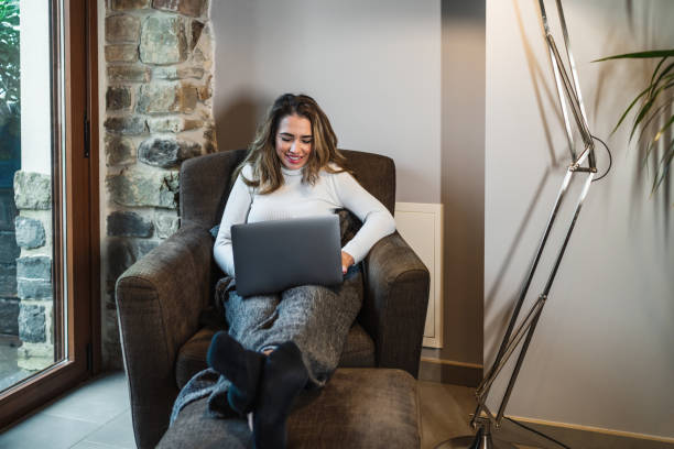 istock Young woman using the computer on the sofa at home. Working remotely at home. Taking courses and learning online via the internet. 1572330675