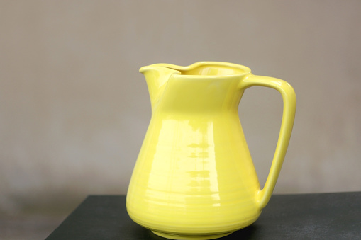 Retro yellow vase on the table, minimal concrete background. Selective focus.