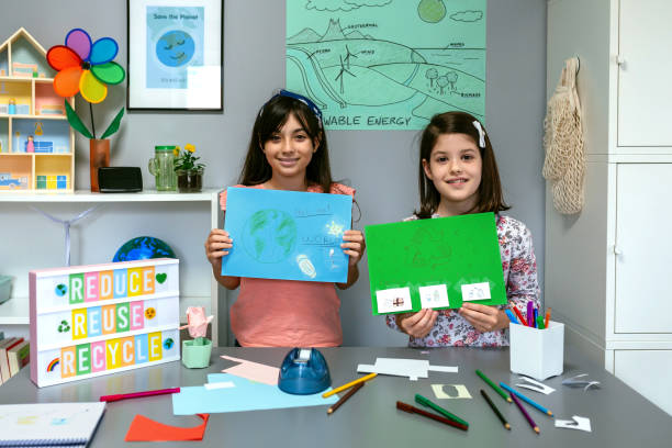 istock Female students looking at camera and showing drawings with ideas to be more ecological 1572340448