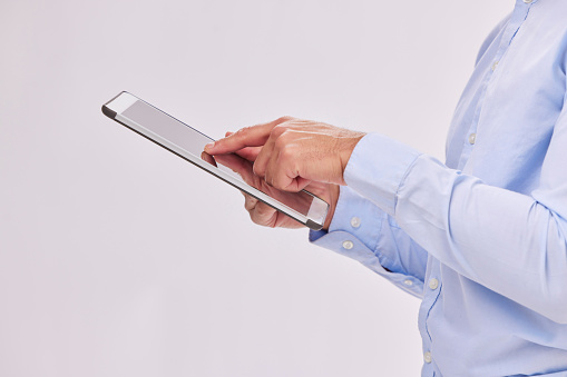 Hands, tablet and business man typing in studio isolated on a white background. Technology, social media and male professional with touch screen for research, web scrolling and internet browsing.