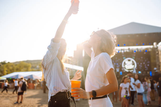 istock Two young girlfriends have fun with beer at the beach party. 1572368620