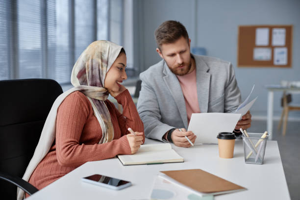 istock Two young intercultural economists discussing financial documents by workplace 1572377437