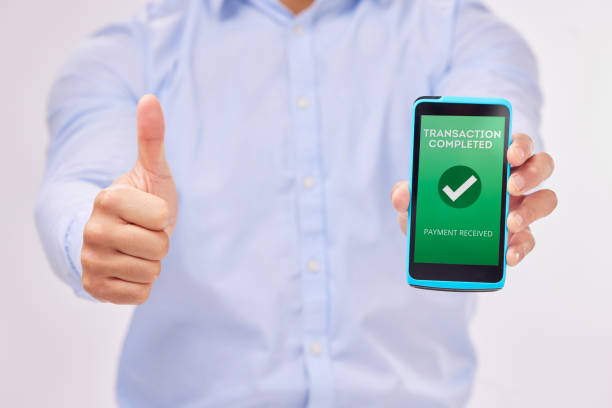 istock Man, hands and phone with thumbs up for transaction approval against a white studio background. Hand of male showing thumb emoji, yes sign or like for electronic purchase or ecommerce on smartphone 1572382297