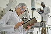 Pretty young woman wearing lab coat in modern factory workshop