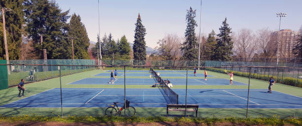New Westminster, British Columbia, Canada- April 28,2023: Public tennis courts with players in Queens Park New Westminster British Columbia. Springtime.