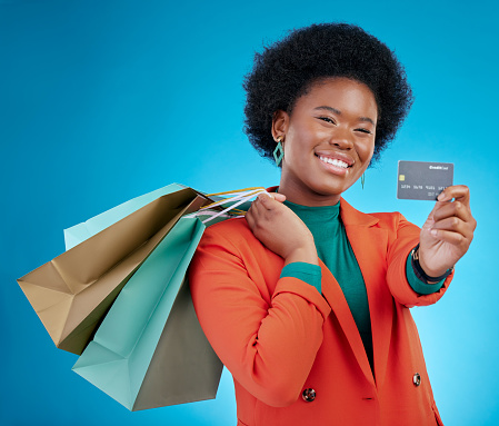 Credit card, shopping offer and woman in portrait for retail banking, finance and e commerce fintech or payment. Customer face, fashion model or african person, bag and debt on blue studio background