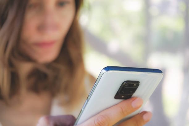 istock woman holding a mobile phone in her hands close-up 1572432163