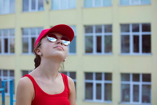Portrait of a teenage girl wearing sunglasses and a hat hanging out on a hot summer day. Reflecting sky in а sunglasses.