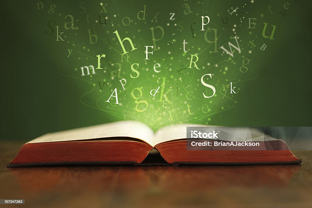 Magic words Book or bible on table with flying letters on green background Book Stock Photo