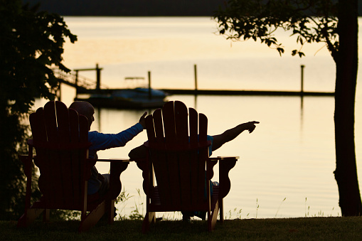 Elderly couple sitting on chairs at sunset on the edge of the property with view of water