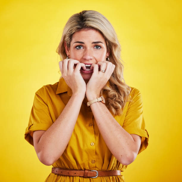 porträt, kauende nägel und frau im studio mit angst, nervös und ängstlich vor gelbem hintergrund. panik, angst und gesicht einer dame mit schlechter angewohnheit, phobie und stress, verängstigt und besorgt über fehler - bad habit fear emotional stress women stock-fotos und bilder