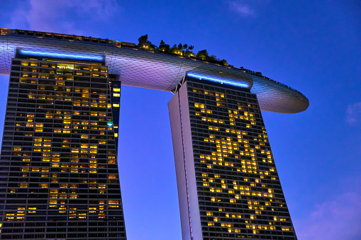 Singapore - Feb 25, 2020. Rear view upshot of part of Marina Bay Sands hotel and center, colorful tropical sunset Singapore. Famous tourist attraction in Marina bay, Bayfront, luxury hotel, casino, convention center. Deep tropical colors of sunset sky. Underexposed, low-light