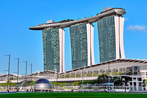 Singapore - Feb 25, 2020. Famous tourist destination - Marina Bay Sands and Shoppes mall in Marina bay, Singapore, on sunny day. Must-see landmarks of city-state, clear blue sky, azure waters. Iconic futuristic architecture and symbols.