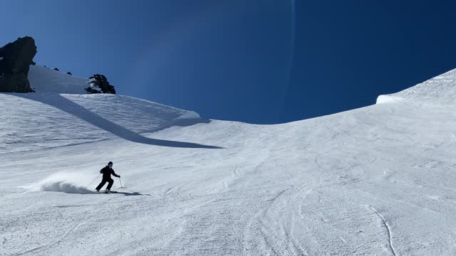 Teenage skier coming down a steep hill on a blue bird day