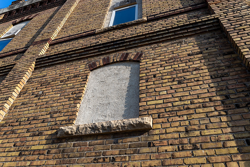 Full frame low angle view of an attractive old mottled yellow and brown color brick wall, with view of an enclosed arched window
