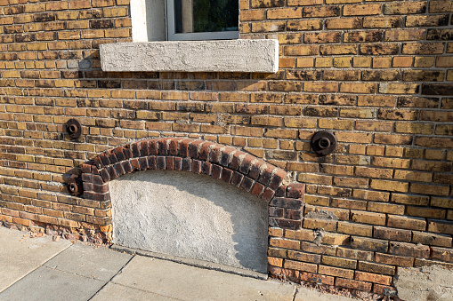 Full frame texture background of an attractive old mottled yellow and brown color brick wall, with view of an enclosed arched basement window