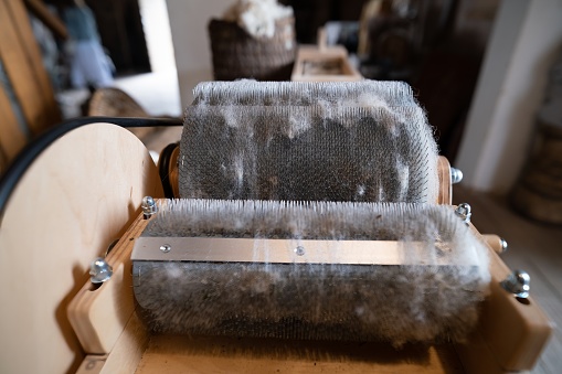 Wool felting. The step of combing the material in a special carding machine. Focus on the background.