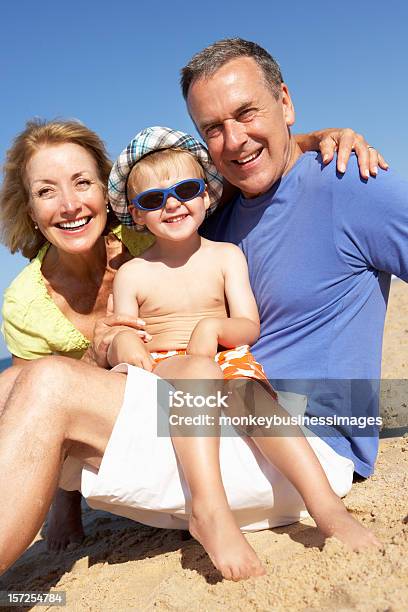 Nonni E Nipote Seduto Sulla Spiaggia - Fotografie stock e altre immagini di Bambino - Bambino, Spiaggia, Anziani attivi