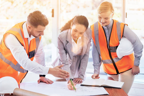istock Architecture, planning and blueprint with people in office for project management, drawing and engineering. Floor plan, documents and teamwork with group of contractors for designer and construction 1572553552
