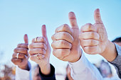 Business people, hands and thumbs up for teamwork, success or winning in thank you and good job outdoors. Hand of group showing thumb emoji, yes sign or like for team approval or ok with blue sky