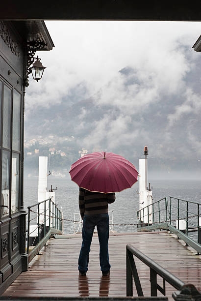 istock Lonely Man Standing With Umbrella Under The Rain In Harbour 157256564