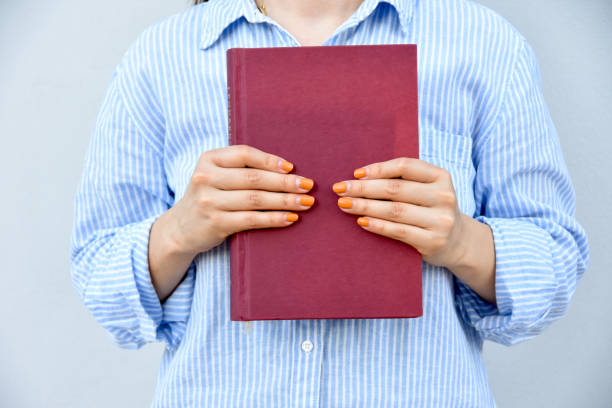 istock Young yoman holding book in her hands, with space  for text. School day concept. 1572576801