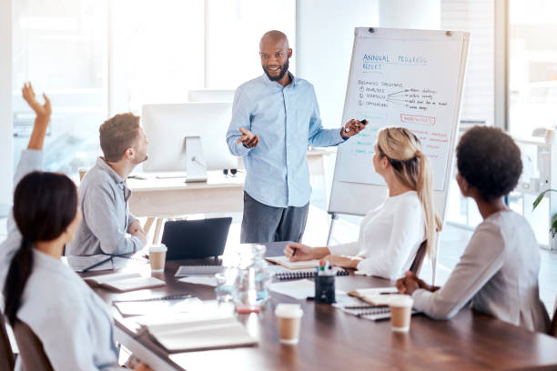 istock Presentation, coaching and question with a business man in the office, talking to a team about our vision. Meeting, teaching and information with an african american male speaker giving a workshop 1572595945