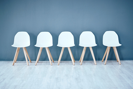 Human resources, hiring and recruitment with a row of chairs in a studio on a gray background waiting area. Interview, room and furniture in an empty or minimalist hr office in a corporate company
