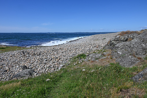 This beach of large pebbles with rocks that roll in the surf is located in Brunlanes, Norway.