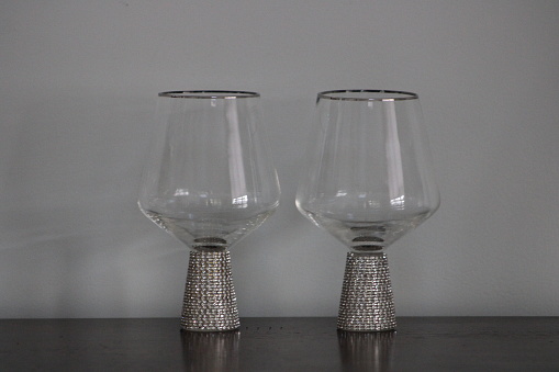 The isolated image of a pair of wine glasses that are bedazzled and sparkly sitting on a table.