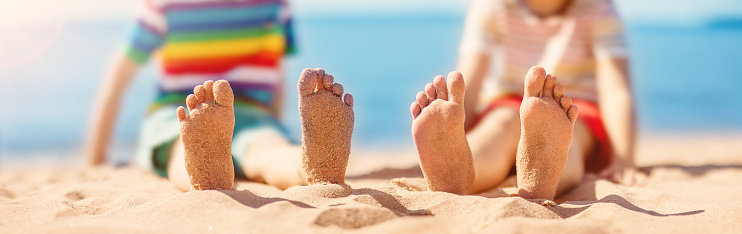 Children sitting on the sand on the beach near the sea. Concept of the family vacation and tourism.