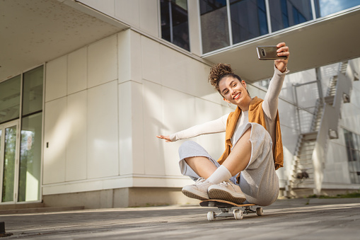 woman caucasian beautiful female have fun with skateboard happy smile take selfie photo self portrait use smarthone mobile phone