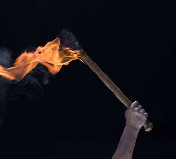 istock burning wooden torch in hand isolated on black background 1572649761