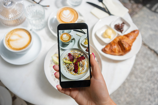 Woman taking photo of breakfast at the cafe on a smartphone