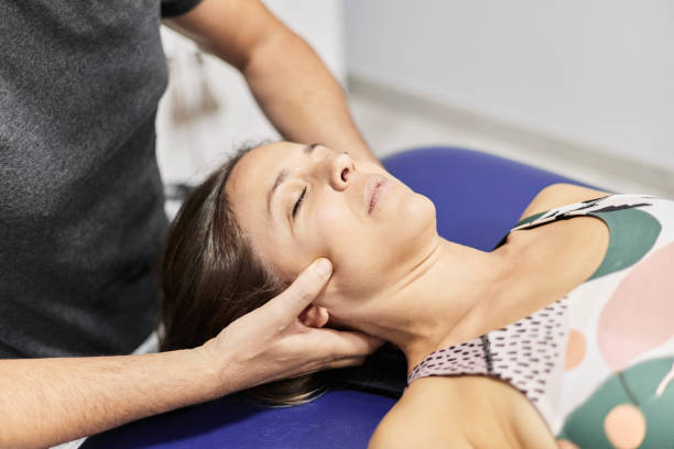 terapeuta anonimo che preme le guance del paziente - osteopath chiropractic adjustment skull massaging foto e immagini stock