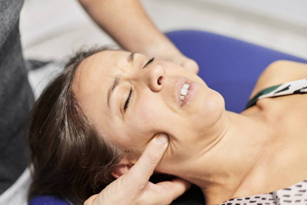 istock Anonymous therapist pressing cheeks of patient 1572720875
