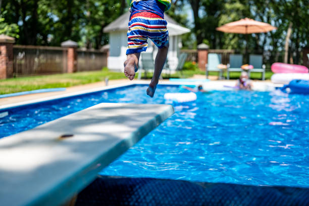 istock Selective focus on a swimming board as a young boy jumps into a pool. 1572730305