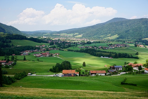 View of a small village in Bavaria in summer. Cute houses in Bavaria in summer. A small village in Ruhpolding in summer on a sunny day. A typical cute village in Bavaria surrounded by greenery.