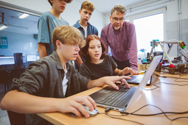 High school student and male teacher learing programming. Group of Gen Z teenage high school students and male teacher, using laptop durning programming lessons. stem topic stock pictures, royalty-free photos & images
