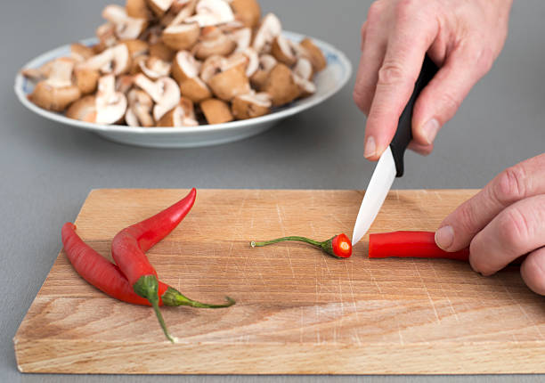 Cutting Red Hot Chili Pepper Male cutting chili pepper in domestic kitchen hott stock pictures, royalty-free photos & images