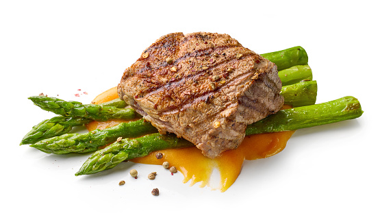 freshly grilled pork fillet steak and asparagus isolated on white background