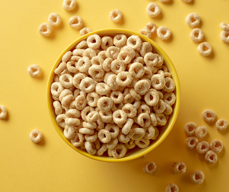 bowl of breakfast cereal honey rings isolated on yellow background, top view